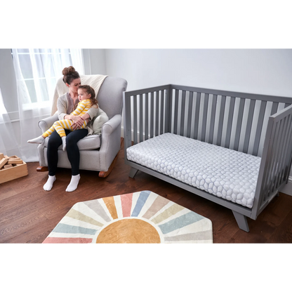 Modugreen Baby Gentle Start breathable crib mattress with 3D lattice cover in a grey crib, next to a mother and child.