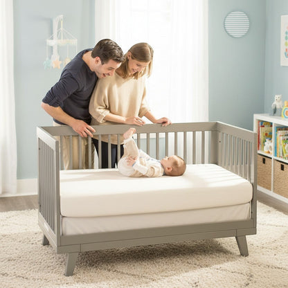 Modugreen Baby organic cotton 2-stage crib mattress in a grey crib with parents watching their baby play.