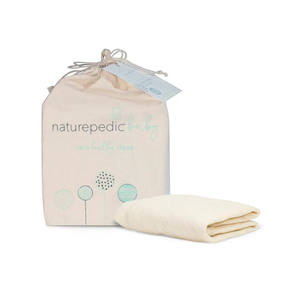 Modugreen Baby organic cotton quilted crib mattress cover in cream, folded next to its branded drawstring storage bag.
