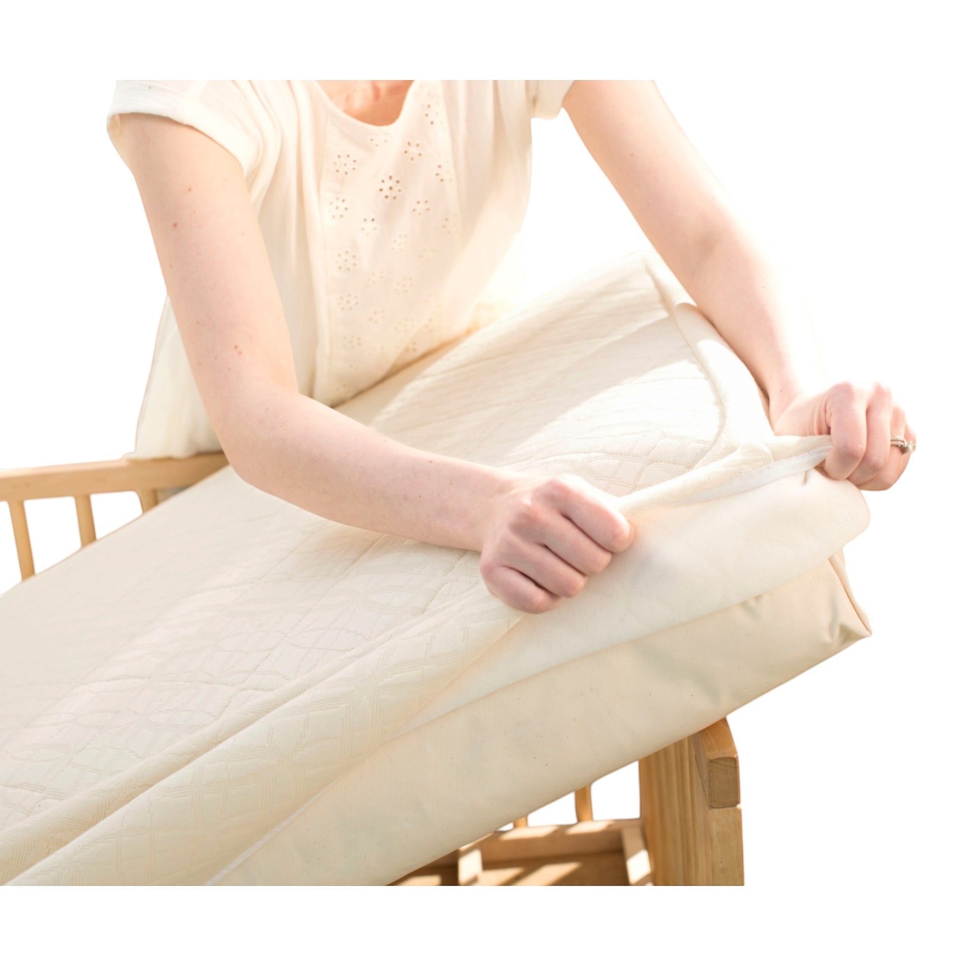 Modugreen Baby organic 2-stage crib mattress with a removable, quilted breathable cover being placed on a crib frame.