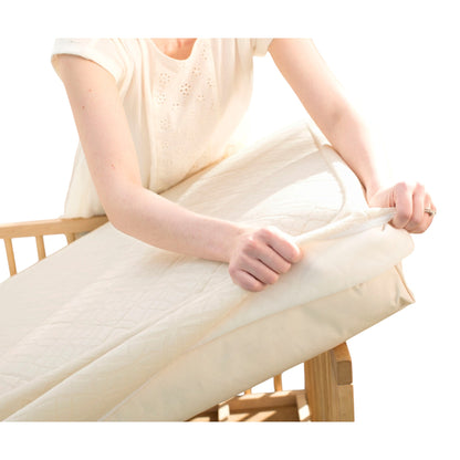 Modugreen Baby organic 2-stage crib mattress with a removable, quilted breathable cover being placed on a crib frame.