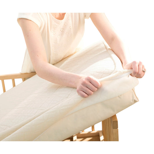 Modugreen Baby organic 2-stage crib mattress with a removable, quilted breathable cover being placed on a crib frame.