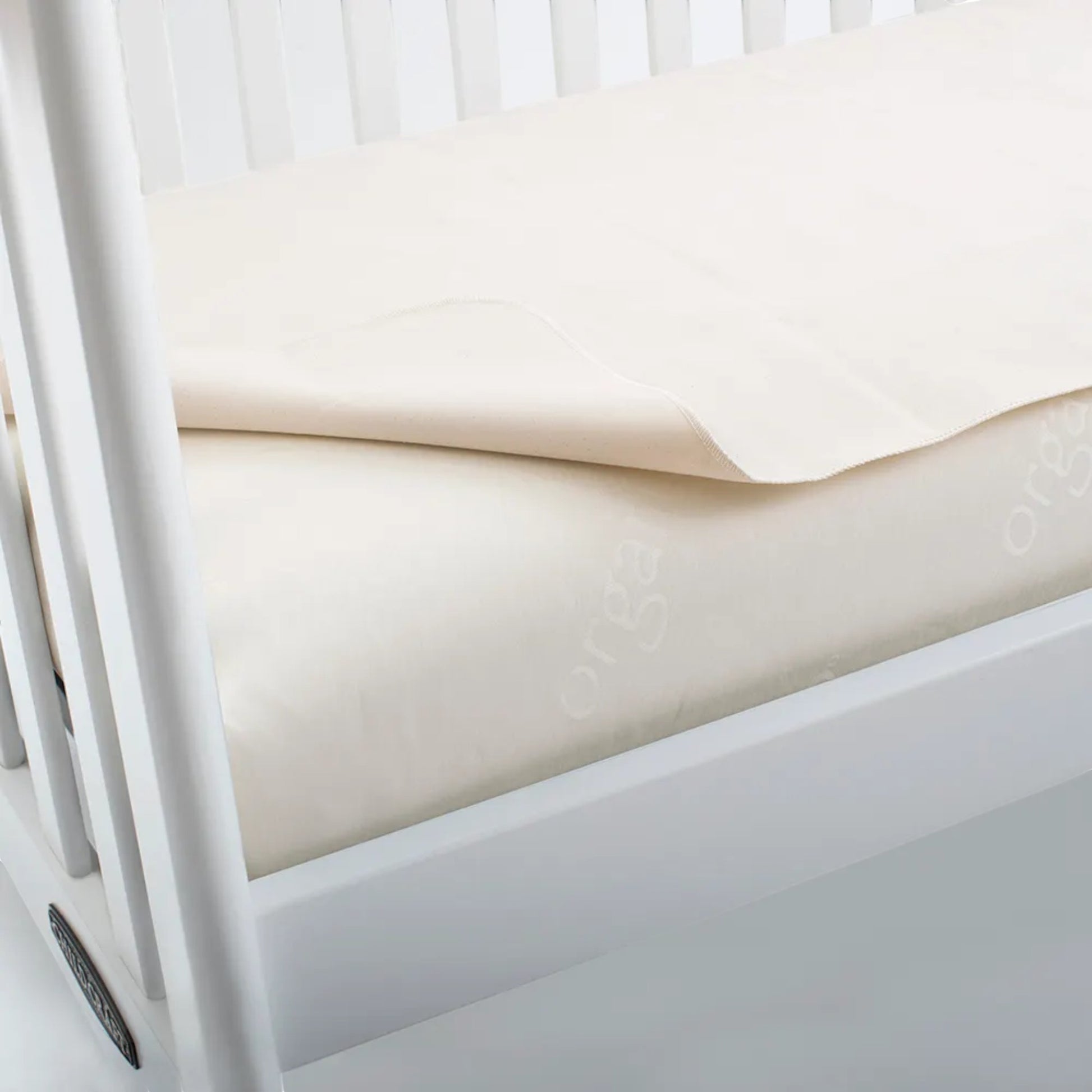 Modugreen Baby flat organic cotton crib mattress protector pad in cream, featuring a soft, breathable design.