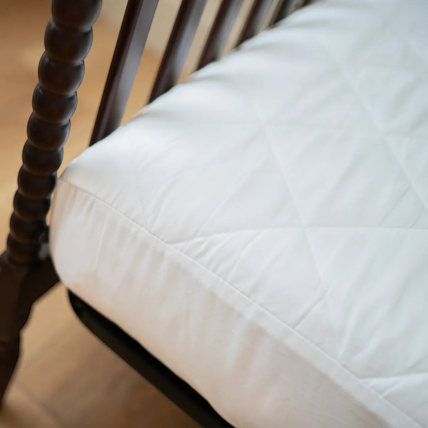 Modugreen Baby white organic quilted waterproof crib mattress protector pad with a soft cotton surface.